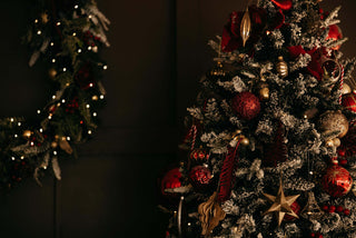 Decorated Christmas tree with red and gold ornaments against a dark background